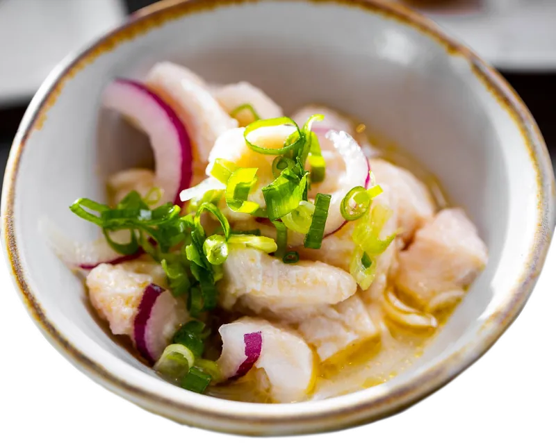 Ceviche de peixe branco com cebola roxa numa tigela de cerâmica.