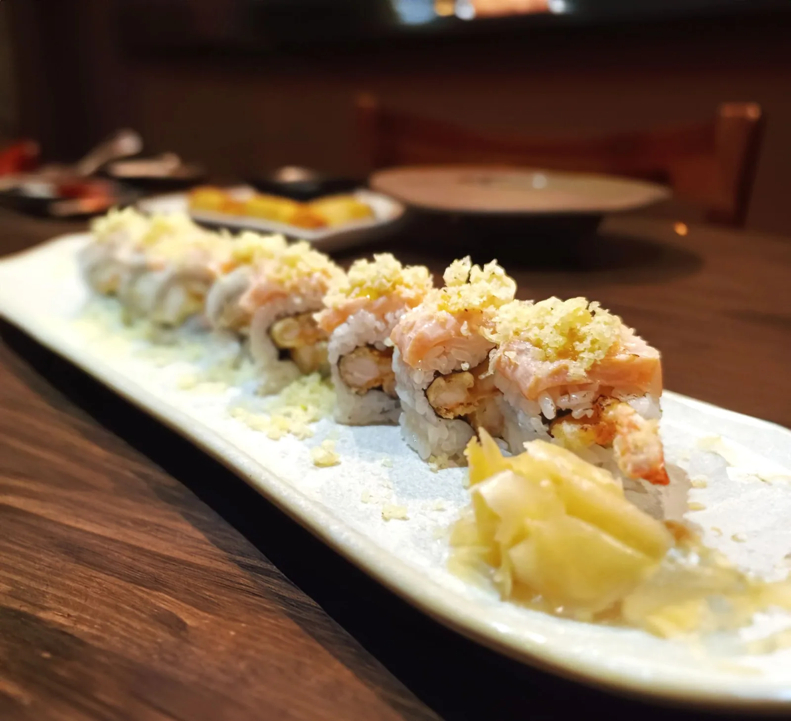 Ebi Honey: uramakis de camarão tempura com salmão por cima, em travessa comprida.