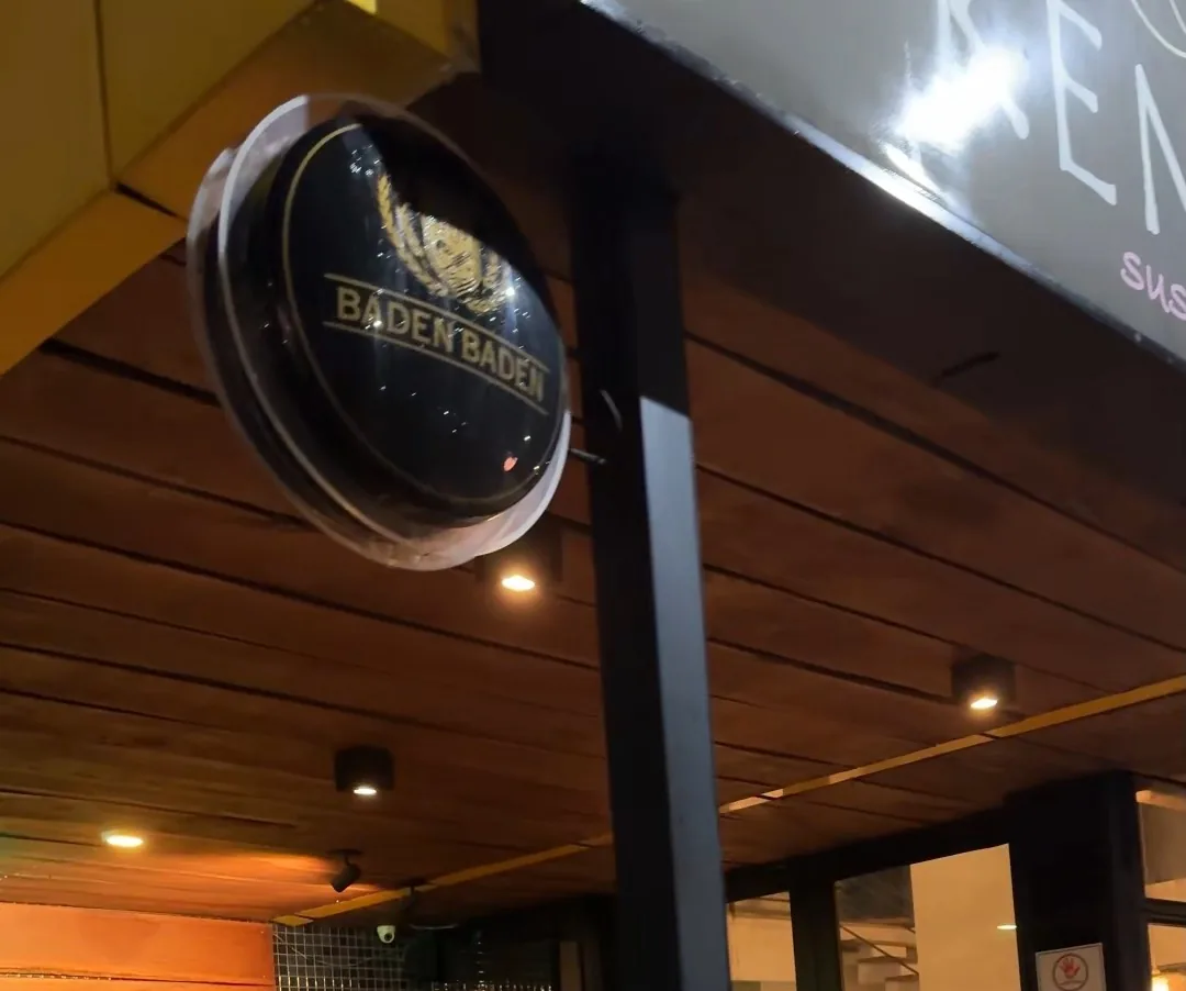Fachada do Kenta à noite, com o teto de madeira, as luminárias acesas e as mesas da área externa.