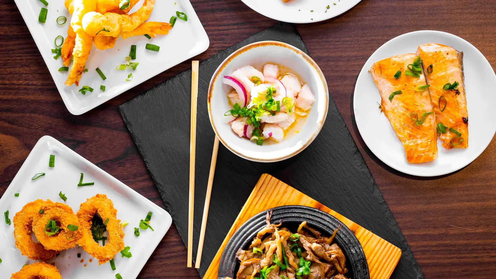 Mesa posta com vários pratos da casa: sushis, entradas, ceviche e pratos quentes.